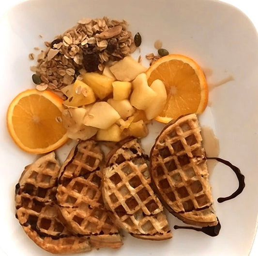 Granolala granola with waffles, fresh fruit and orange slices on plate